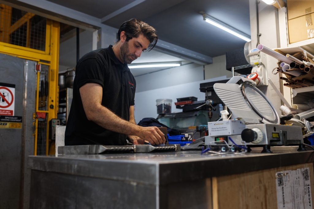 commercial catering engineer in workshop repairing oven
